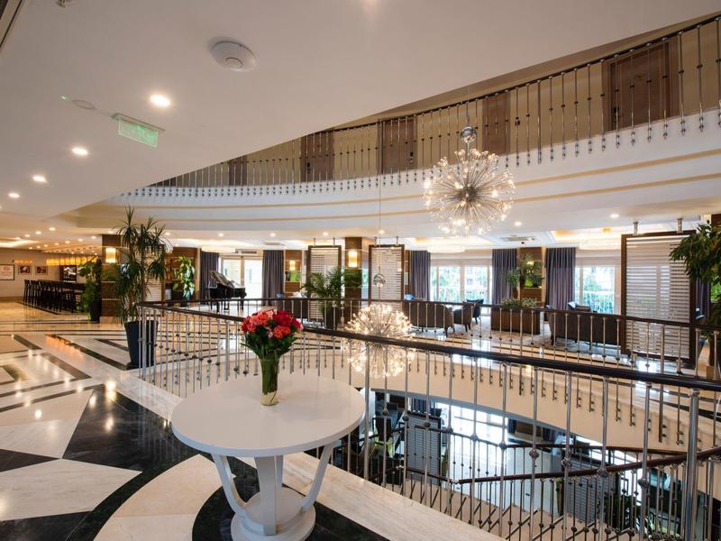 Eleganter Innenraum mit weißem Rundtisch, roten Rosen, schwarzen und weißen Fliesen und Kronleuchtern.