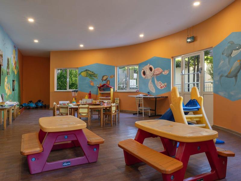 Bunter Spielraum mit Tischen, Bänken und Tiermotiven an den Wänden in einem Hotel.