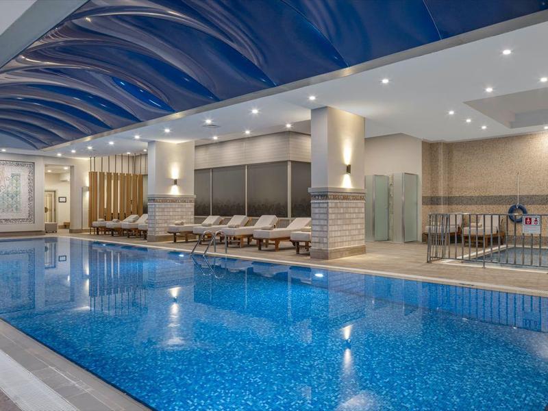 Moderner Innenpool mit blauen Wänden und bequemen Liegestühlen in einem Hotel.