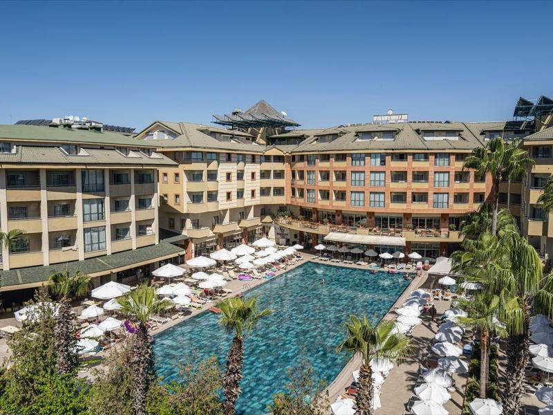 Großes Resort mit einem zentralen Pool, umgeben von Liegestühlen und Gebäuden mit Balkon