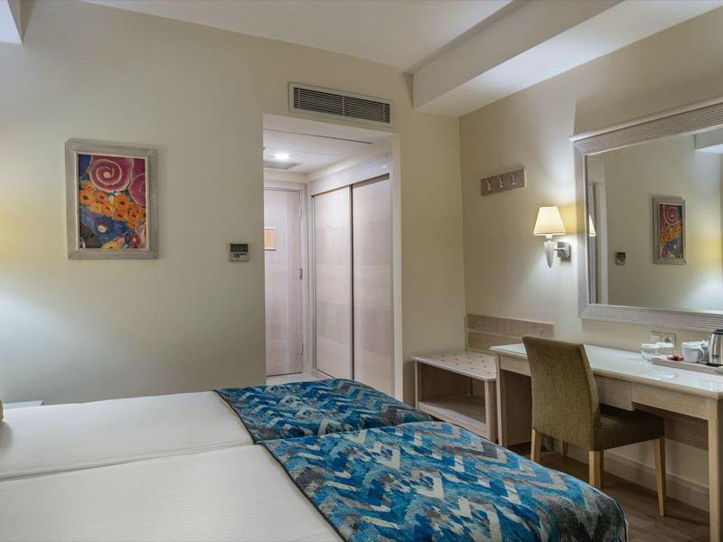 Hotelzimmer mit zwei Betten, Schreibtisch, Spiegel und TV an der Wand.