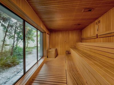 Helle Holzsauna mit Fensterblick auf schneebedeckte Bäume und Pflanzen.