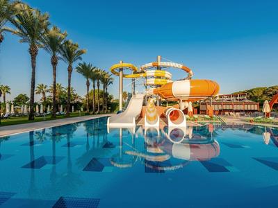 Wasserpark mit Rutschen und Palmen neben einem großen Pool unter blauem Himmel