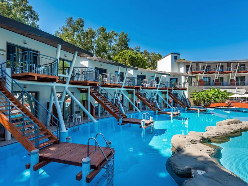 Hotel mit mehreren Zimmern und privaten Zugängen zu einem großen Pool mit Sonnenterrassen und Schwimmern.