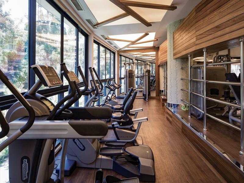 Moderner Fitnessraum mit Rudergeräten neben großen Fenstern und Holzboden.