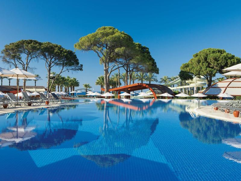 Ruhebereich mit blauem Pool, Liegestühlen und Sonnenschirmen unter klarem Himmel