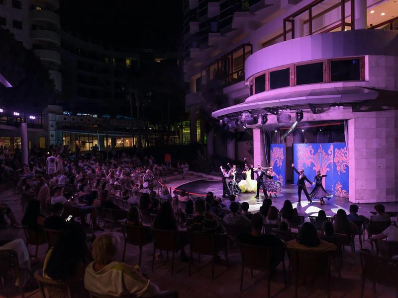 Abendliche Aufführung mit Tänzern und Publikum in einem offenen Bereich eines Hotels.
