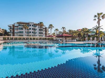 Large hotel pool with sun umbrellas and palm trees on a sunny day