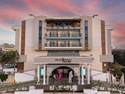 Modern hotel building with balconies and a colorful sunset sky in the background.