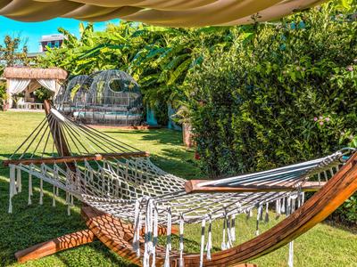 Hammock in garden with green lawn and bushes, ideal for relaxing on vacation.