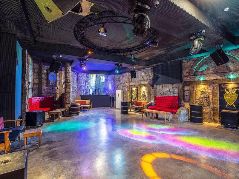 Ampia sala per feste moderna con illuminazione colorata e zone salotto.