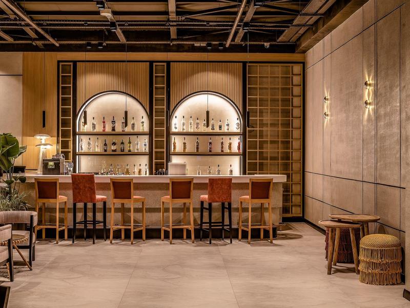 Bar dell'hotel moderno con scaffali illuminati e sgabelli in pelle