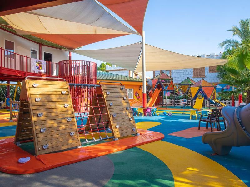 Area giochi all'aperto colorata con attrezzature per arrampicata e vele ombreggianti sotto un cielo limpido