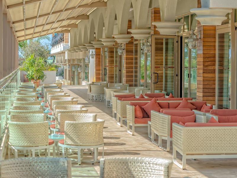 Grande terrazza coperta dell'hotel con aree salotto, tavoli e sedie