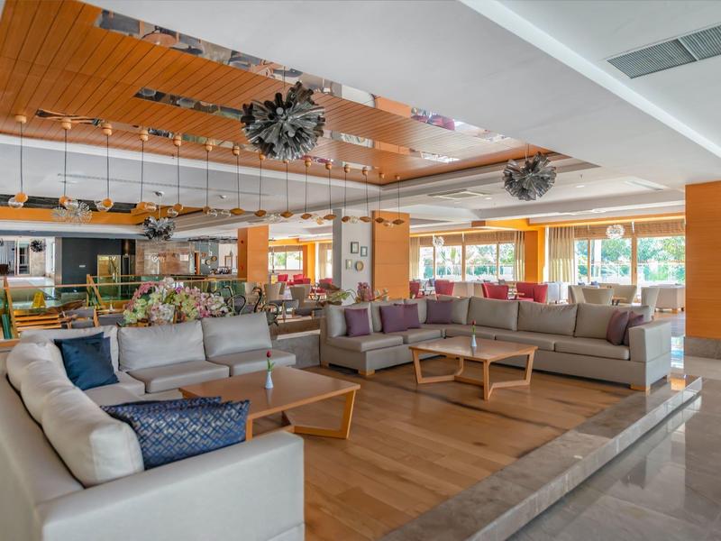 Ampia hall dell'hotel con aree salotto moderne, pavimento in legno e grandi finestre con luce naturale.