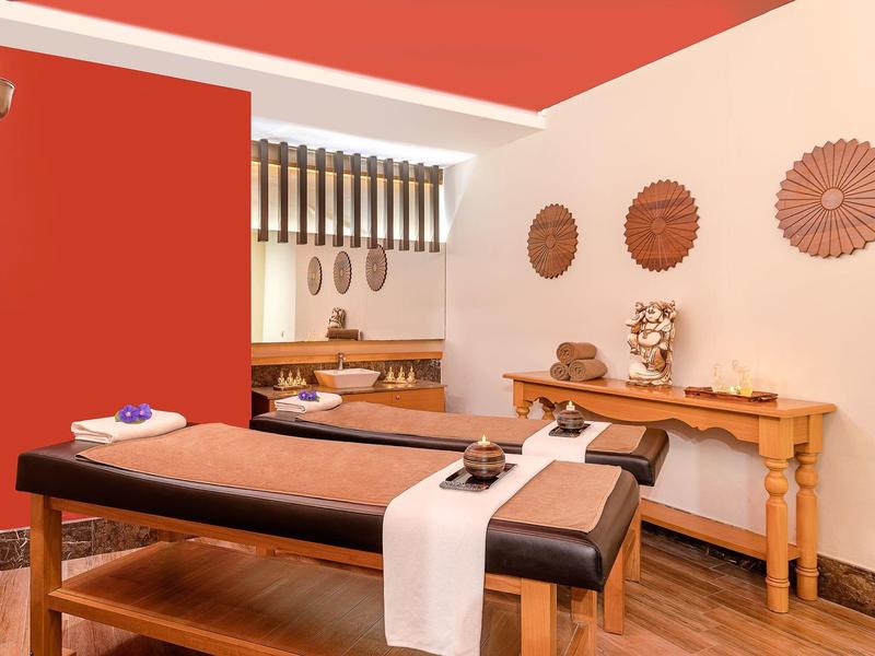 Sala spa tranquilla con lettino da massaggio, decorazioni murali e atmosfera rilassante.