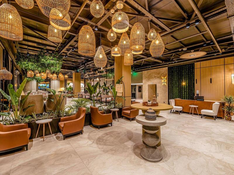 Lobby dell'hotel con poltrone, piante e decorazioni in legno caldo.