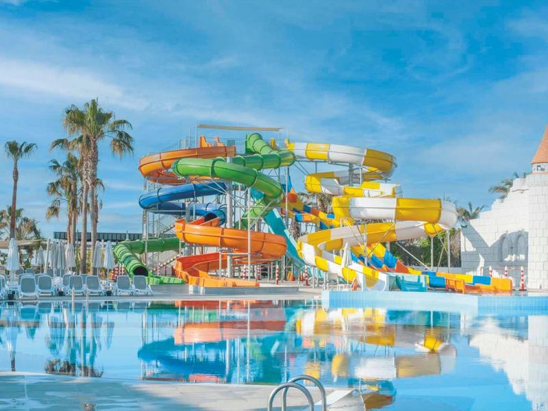 Scivoli d'acqua colorati sopra una grande piscina dell'hotel con cielo azzurro terso sullo sfondo