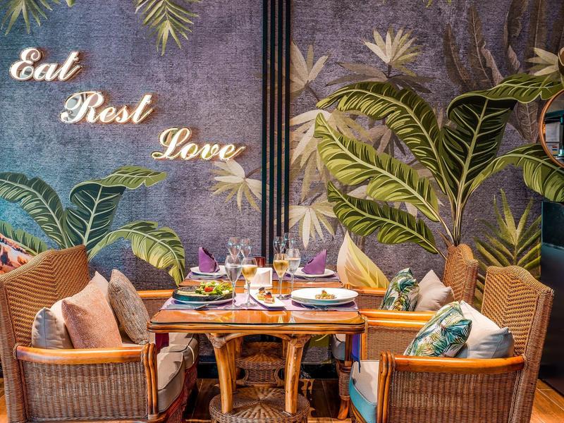 Accogliente zona pranzo con mobili in bambù e decorazioni murali esotiche in un hotel