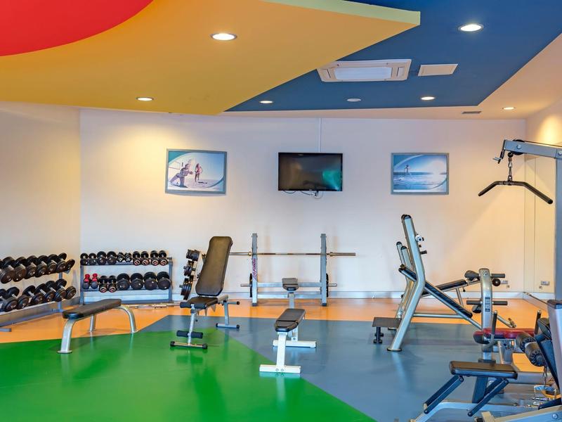 Gimnasio con pesas, equipos de entrenamiento y techo y suelo coloridos en un hotel