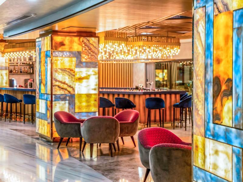 Bar de hotel modernamente decorada con paredes de vidrio de colores y asientos acogedores.