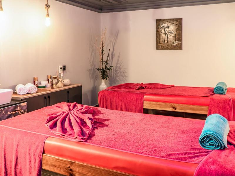 Mesa de masaje roja con toallas en una sala de bienestar con luz cálida.