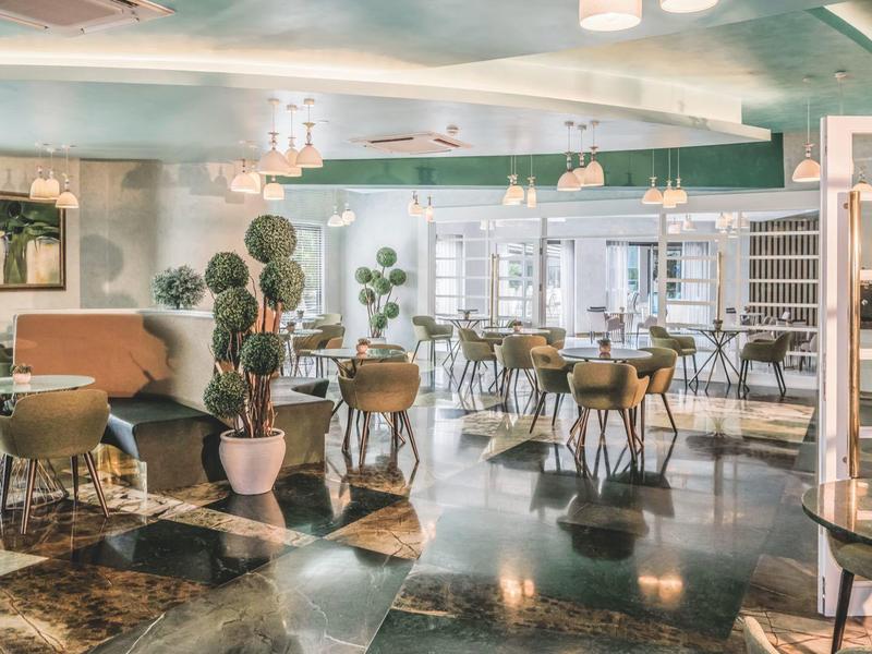 Restaurante elegante del hotel con mesas redondas, sillas y lámparas modernas en ambiente luminoso.