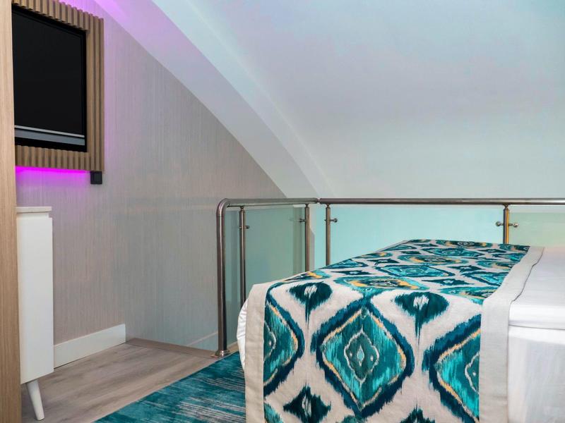 Habitación moderna en ático con puerta de vidrio y cubre cama azul estampado sobre la cama.