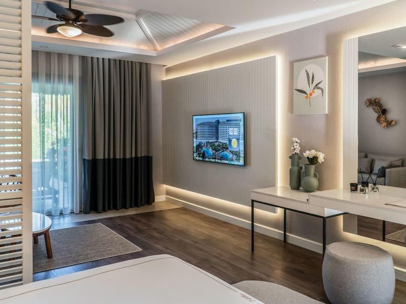 Habitación de hotel moderna con escritorio elegante, televisor e iluminación indirecta.