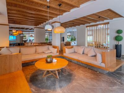 Modern hotel lounge area with comfortable sofas, round wooden table, and stylish lighting.
