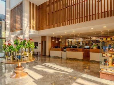 Luminosa hall dell'hotel con reception, aree salotto e ampie finestre che lasciano entrare molta luce naturale.