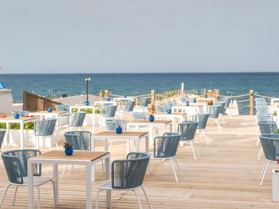 Open terrace with chairs and tables by the sea under cloudy sky with Turkish flag.