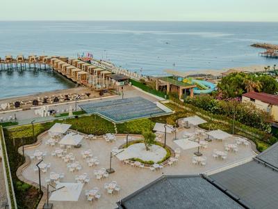 Luxury hotel complex with pools, sun loungers, and sea access via a long pier.