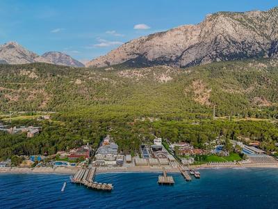Aerial view of a beach resort with wooden piers in front of mountains and forested hills.