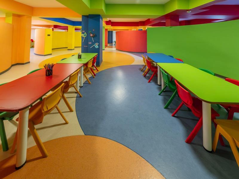 Colorful play and dining area with long tables and chairs in vibrant colors.