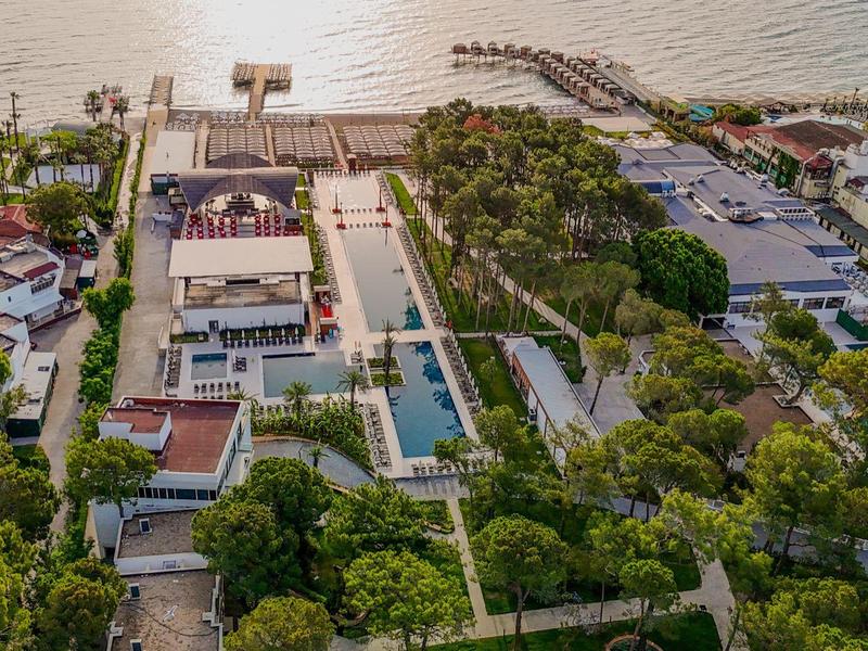 Aerial view of a hotel with pool, garden, and waterfront access with boat dock