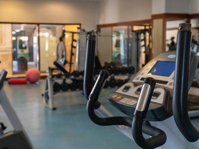 Interiér hotelové posilovny s fitness vybavením a činkami.