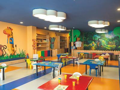 Sala giochi colorata per bambini con tavoli, sedie e murales in un hotel