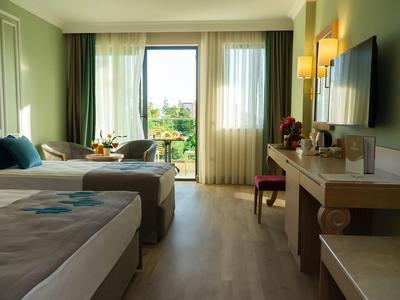 Camera d'hotel moderna con due letti, ampia finestra e scrivania con TV.