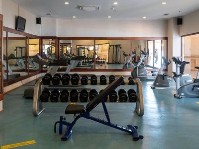 Helder verlichte hotelgym met vrije gewichten en cardioapparaten.