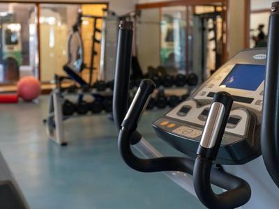 Moderne fitnessapparatuur in een lichte hotelgym met spiegels aan de muren.