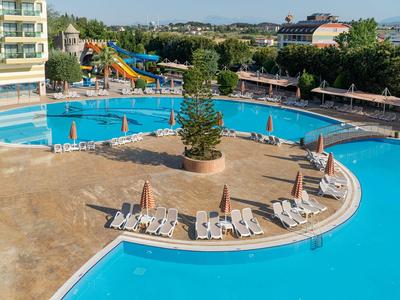 Groot buitenzwembad met blauwe glijbanen, ligstoelen en parasols bij een hotelresort.