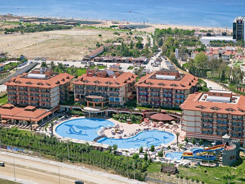 Grande resort con più edifici e una grande piscina in posizione soleggiata.