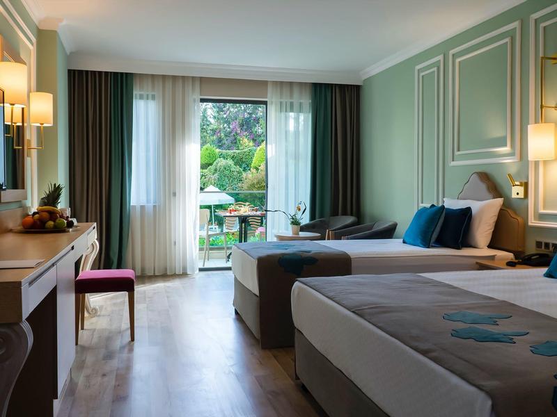 Camera d'hotel moderna con letti matrimoniali e vista su un balcone.