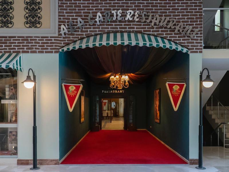 Ingresso con tappeto rosso e gagliardetti in un hotel o locale elegante.