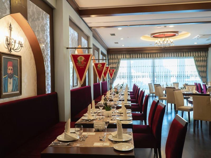 Ristorante elegante con tavoli apparecchiati e decorazioni rosse in un hotel.