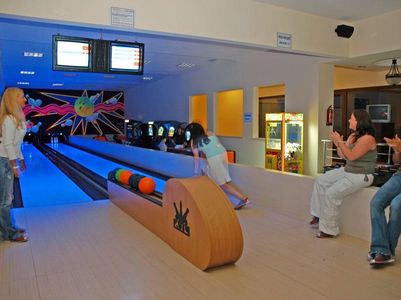 Interno di una pista da bowling con giocatori e palle colorate.