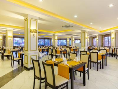 Restaurante de hotel luminoso y elegante con paredes amarillas y mesas y sillas bien dispuestas.