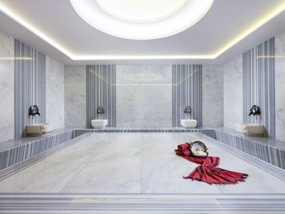 Hamam turco moderno con altas columnas de mármol y toallas rojas en el suelo.