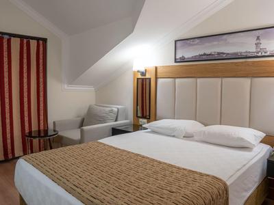 Chambre d'hôtel moderne avec un lit double confortable, un fauteuil, des rideaux et une décoration murale.